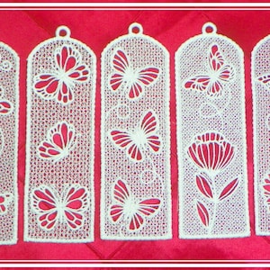 May include: Five white lace bookmarks with butterfly and floral designs. The bookmarks are on a red background.