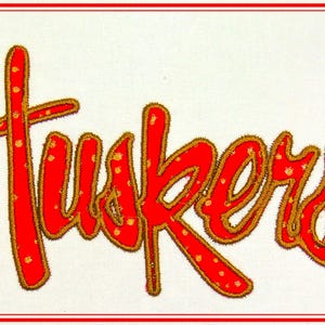 May include: Red and gold embroidered patch with the word "Huskies" in a stylized font.