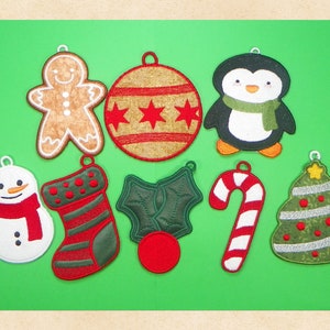 May include: Eight Christmas ornaments with various designs, including a gingerbread man, a snowman, a stocking, a candy cane, a holly sprig, a Christmas tree, a penguin, and a red and gold bauble.