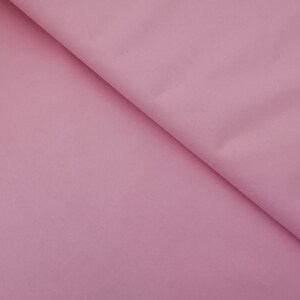 May include: A close-up of a smooth, pale pink fabric. The fabric is folded in half, creating a soft, gentle curve.