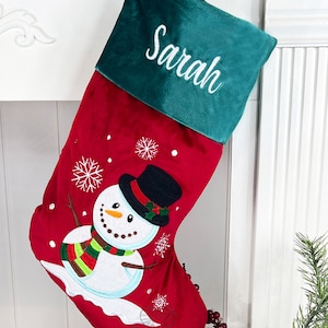 May include: Red and green Christmas stocking with a snowman design and the name "Sarah" embroidered on the cuff.