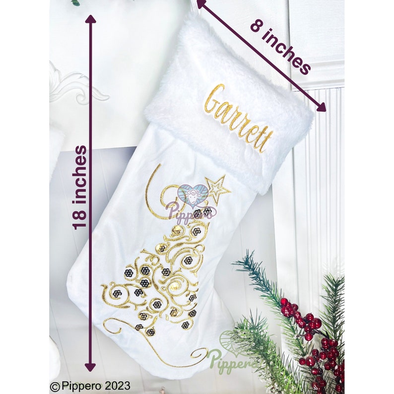 May include: White Christmas stocking with a gold embroidered Christmas tree design and the name "Garrett" embroidered on the cuff. The stocking is 18 inches tall and 8 inches wide.