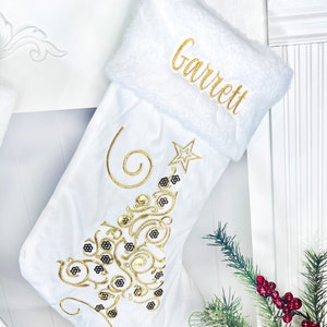 May include: White Christmas stocking with a gold embroidered Christmas tree design and the name "Garrett" embroidered on the cuff.
