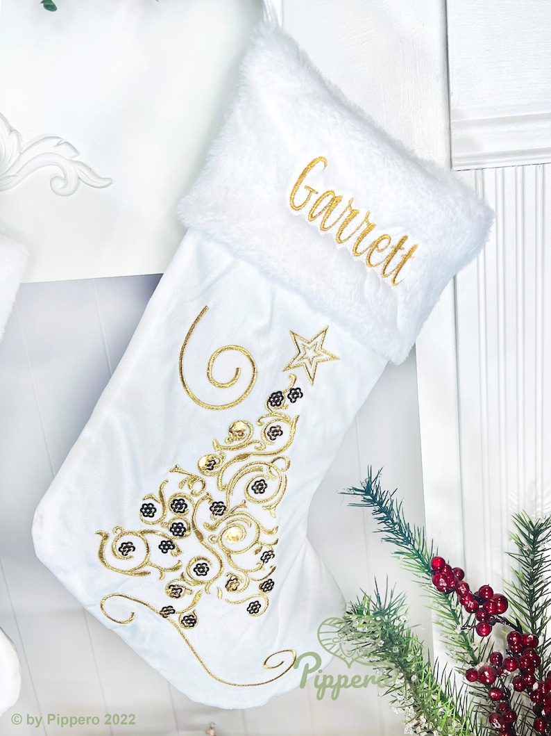 May include: White Christmas stocking with a gold embroidered Christmas tree design and the name "Garrett" embroidered on the cuff.