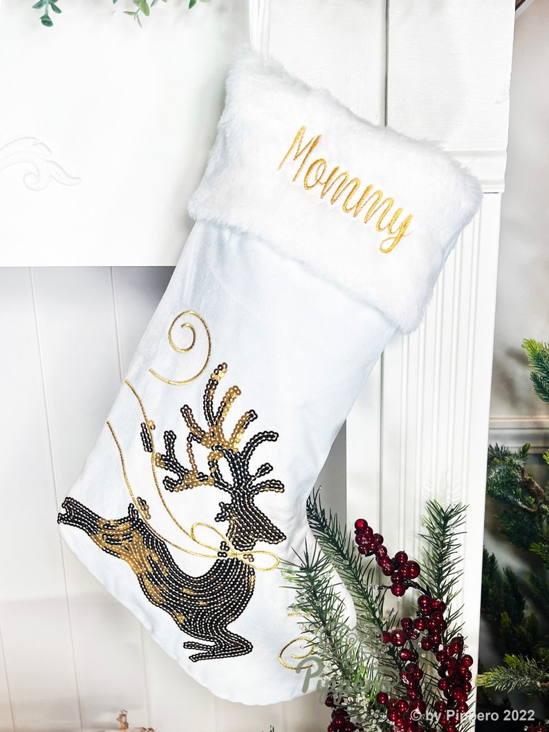 May include: White Christmas stocking with a gold embroidered "Mommy" on the cuff and a black and gold sequined reindeer design.