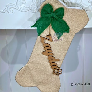May include: A burlap dog bone stocking with a green burlap bow and a wooden name tag that says "Zayda" with a paw print.