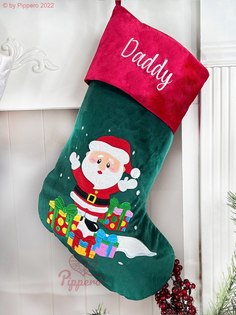 May include: Green Christmas stocking with a red cuff and the word "Daddy" embroidered on it. Santa Claus is embroidered on the stocking with presents and snowflakes.