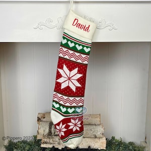 May include: White knitted Christmas stocking with a red and green snowflake pattern. The stocking has a white cuff with the name "David" embroidered in red.