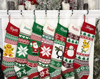 May include: Seven personalized Christmas stockings with red, green, and white knitted patterns. The stockings feature various holiday designs, including a gingerbread man, a snowflake, Santa Claus, a penguin, a snowman, a reindeer, and a deer. The stockings are hung on a white fireplace mantel.