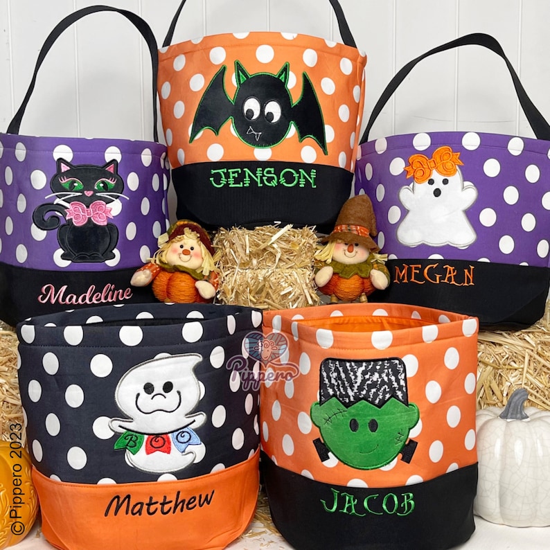 May include: Five Halloween trick-or-treat bags with different designs and names. The bags are made of fabric with polka dots and feature embroidered images of a bat, ghost, black cat, Frankenstein, and a ghost with a BOO banner. The bags have black and orange trim and are personalized with the names Jenson, Megan, Madeline, Matthew, and Jacob.