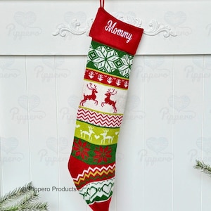 May include: Red and green Christmas stocking with a white snowflake pattern, reindeer, and a red poinsettia. The stocking has a red cuff with the word "Mommy" embroidered in white.
