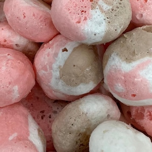 May include: Close-up of a group of round, pink, brown, and white bath bombs. The bath bombs have a marbled appearance.