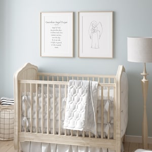 May include: A white cot with a white quilted blanket and a white frilled skirt. Two framed prints hang on the wall behind the cot. The print on the left has the text "Guardian Angel Prayer" and a prayer. The print on the right is a line drawing of an angel holding a baby.