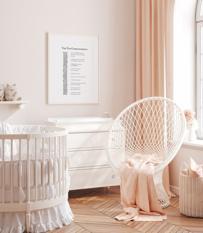 May include: A white crib with a white and gray bedding set, a white dresser, a white chair with a pink blanket, and a framed print of the Ten Commandments on a pink wall.