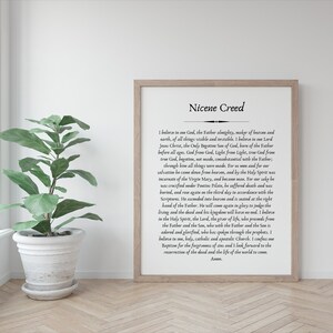 May include: A framed print with a black and white text of the Nicene Creed. The text is centered on a white background with a black border. The frame is a light brown wood.