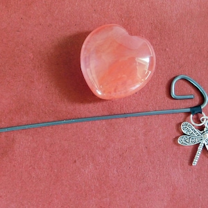 May include: A pink heart-shaped crystal charm attached to a silver dragonfly bookmark.