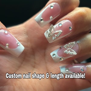 May include: Pink and white square-shaped acrylic nails with silver butterfly accents and rhinestones. Custom nail shape and length available.