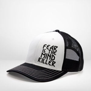 May include: A white and black trucker hat with a black embroidered message that reads "FEAR IS THE MIND KILLER".