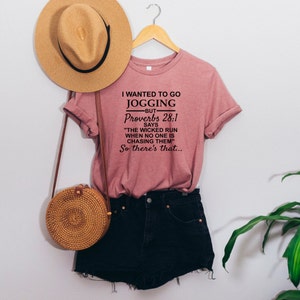 May include: A pink t-shirt with a black graphic that says "I wanted to go jogging -but- Proverbs 28:1 says "The wicked run when no one is chasing them" So there's that..."