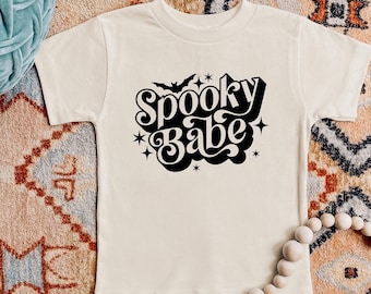Könnte beinhalten: Ein weißes T-Shirt mit einer schwarzen Grafik, auf der "Spooky Babe" mit einer Fledermaus und Sternen steht.