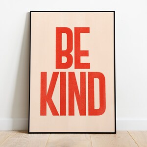 Puede incluir: Un p&oacute;ster enmarcado con fondo melocot&oacute;n y las palabras "BE KIND" en letras rojas y negritas.