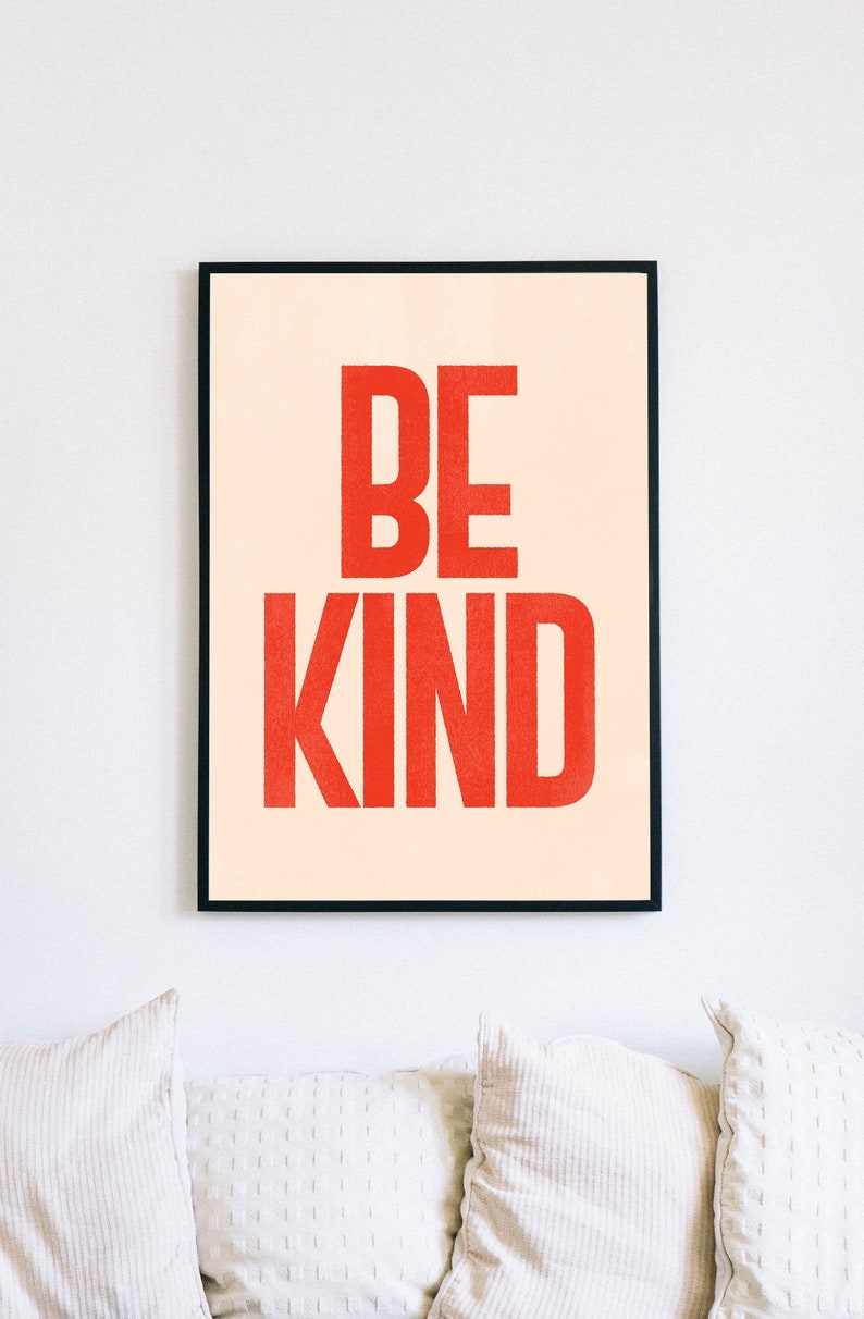 Puede incluir: Una impresi&oacute;n enmarcada con un fondo melocot&oacute;n y las palabras "BE KIND" en letras rojas y negritas.