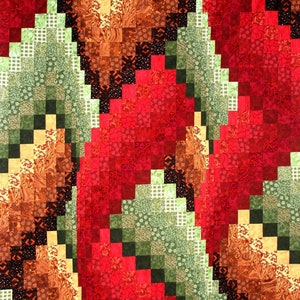 May include: A quilt made of colorful fabric squares in shades of red, green, brown, and black. The squares are arranged in a pattern that creates a swirling effect.