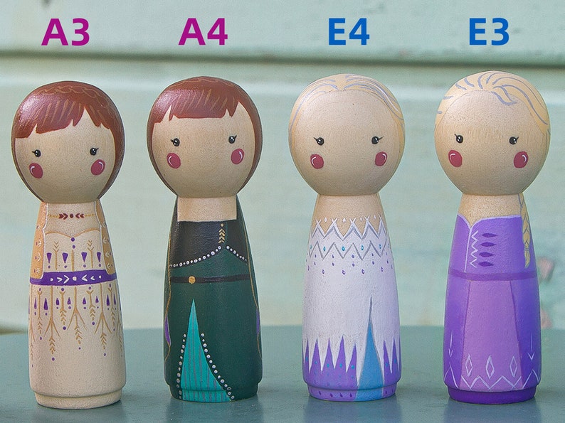 Puede incluir: Cuatro mu&ntilde;ecas de madera de clavija, cada una con un peinado y un vestido diferentes. Las mu&ntilde;ecas est&aacute;n pintadas con detalles intrincados, que incluyen un vestido dorado y morado, un vestido verde y azul, un vestido blanco y morado y un vestido morado con una trenza.