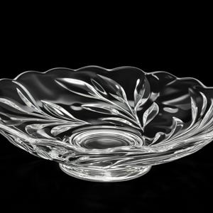 May include: Clear glass serving bowl with a leaf design. The bowl has a scalloped edge and sits on a round base. The leaf pattern is etched into the glass, creating a decorative and elegant look. Perfect for serving salads or fruit.