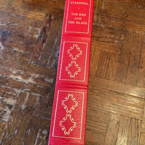 May include: A red hardback book with gold lettering on the spine. The title is "STENDHAL THE RED AND THE BLACK".