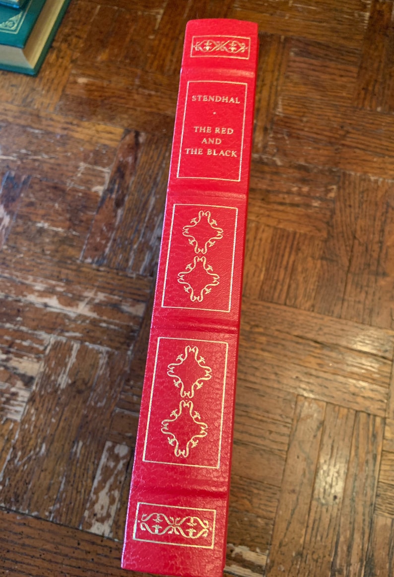 May include: A red hardback book with gold lettering on the spine. The title is "STENDHAL THE RED AND THE BLACK".