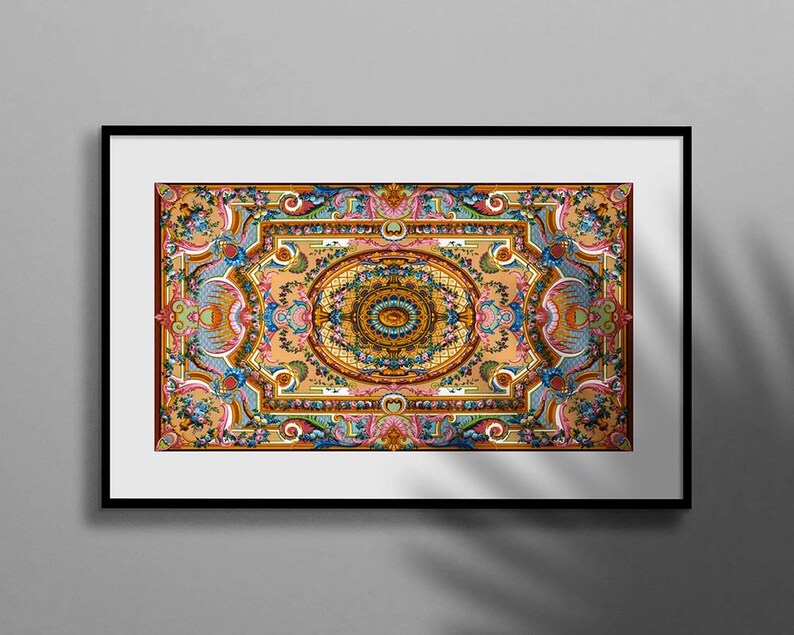 May include: A framed print of a colourful, intricate, symmetrical design with a central eye motif. The design features floral and geometric patterns in shades of blue, green, yellow, orange, and red.