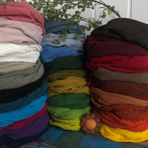 Könnte beinhalten: Ein Stapel von 20 Stoffquadraten in verschiedenen Farben, darunter Rot, Blau, Grün, Gelb, Braun und Schwarz. Die Stoffquadrate sind in zwei Spalten angeordnet, mit einer Blumendekoration in der Mitte.