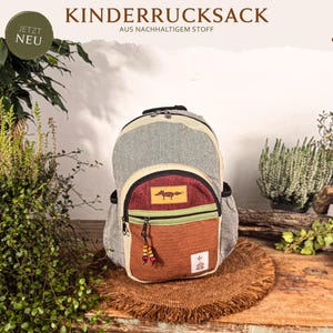 Könnte beinhalten: Ein Kinderrucksack mit grauem Fischgrätenmuster, einer kastanienbraunen Vordertasche mit Fuchsgrafik und einer rostfarbenen unteren Tasche. Der Rucksack hat schwarze Reißverschlüsse mit bunten Holzperlen und ein kleines weißes Logo-Etikett unten.