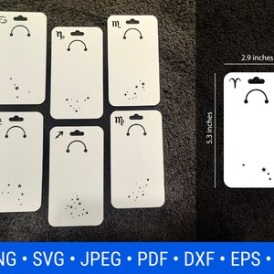 May include: Set of 7 white blank earring display cards with black zodiac symbols and constellation outlines. Each card measures 13.5 cm by 7.4 cm.