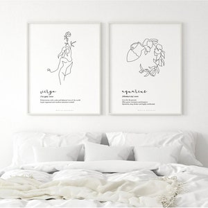 May include: Two framed art prints featuring minimalist line drawings of the Virgo and Aquarius zodiac signs. The Virgo print depicts a woman holding a flower, while the Aquarius print shows a water bearer. Each print includes the sign's name and a brief description.