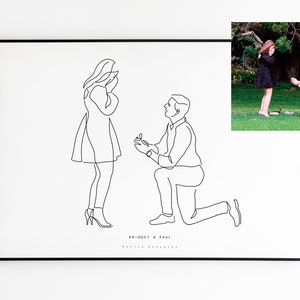 May include: A framed black and white line art print depicting a marriage proposal. The artwork shows a man kneeling and offering a ring to a woman. The names "Bridget & Paul" are printed below the figures. A color photo of the couple is in the upper right corner.