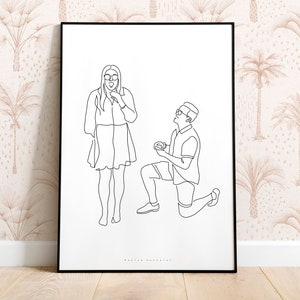 May include: Black framed line art print depicting a marriage proposal. A person kneels, presenting a ring to another person. The background features a beige wallpaper with a palm tree pattern.