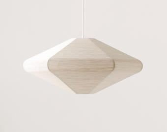 May include: A modern, geometric pendant light fixture. The light has a diamond-like shape with rounded edges, constructed from a light beige woven material. It hangs from a white cord against a plain white background, suitable for home decor.