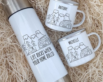 May include: White insulated travel mug with the text "Life rocks when your home rolls!" and a black and white illustration of a camper van, mountains, and trees. Two white enamel mugs with black and white illustrations of a camper van, mountains, and trees. The mugs are labeled "Antony" and "Michelle".