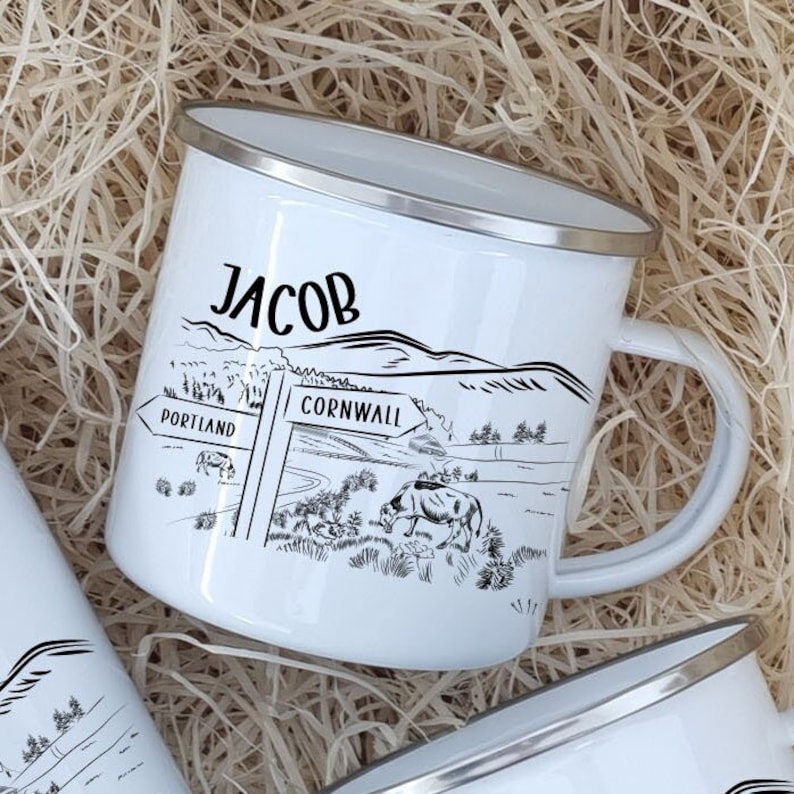 K&ouml;nnte beinhalten: Eine wei&szlig;e Emailletasse mit einer Schwarzwei&szlig;illustration eines Wegweisers mit den Worten "Portland" und "Cornwall" darauf. Die Tasse tr&auml;gt au&szlig;erdem den Namen "Jacob" aufgedruckt.