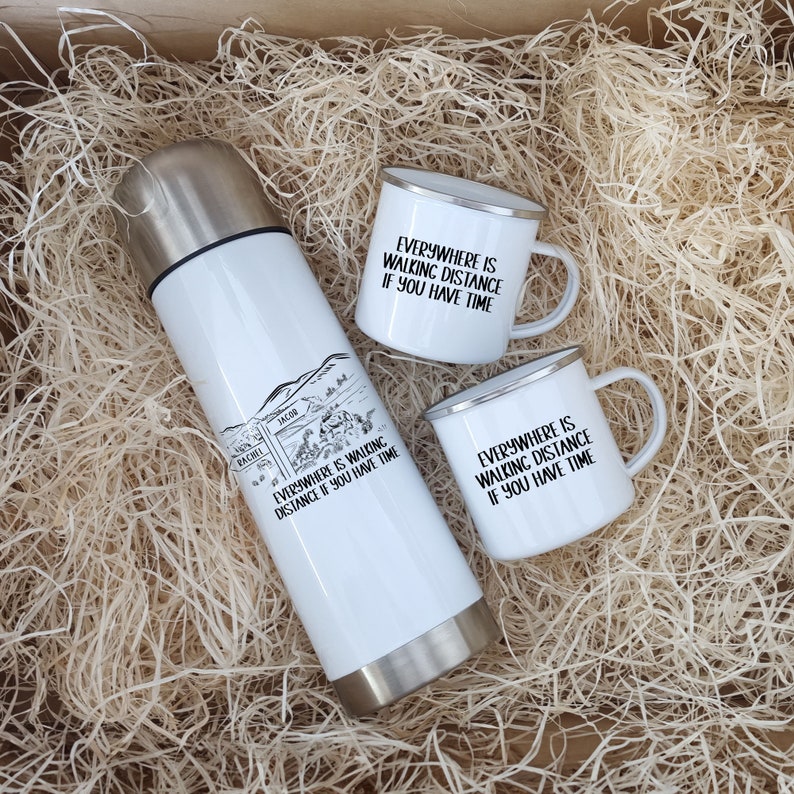 K&ouml;nnte beinhalten: Eine wei&szlig;e isolierte Wasserflasche und zwei wei&szlig;e Emailletassen mit schwarzem Text, der "Everywhere is walking distance if you have time" lautet. Die Artikel befinden sich in einer Schachtel, die mit wei&szlig;en Verpackungschips gef&uuml;llt ist.