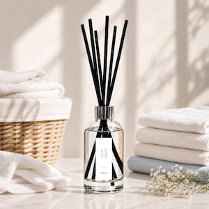May include: A clear glass reed diffuser bottle with a silver collar and seven black reeds. The white rectangular label features the text Fresh Laundry and the brand name organico. The bottle contains a clear liquid fragrance oil.