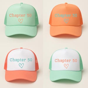May include: Four trucker hats in various colors: mint green, orange, white, and a combination of white and orange. Each hat features the text "Chapter 50" above a heart symbol, all in a coordinating color.