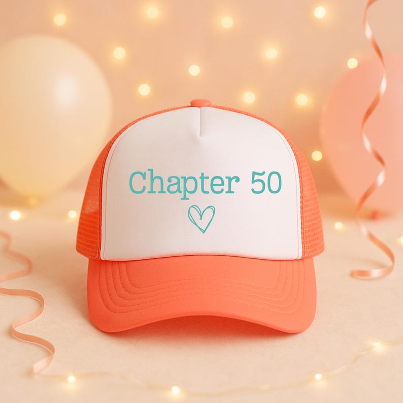 May include: An orange and white trucker hat with the text "Chapter 50" and a heart symbol in teal. The hat has a mesh back and a curved brim. The background includes balloons and string lights.