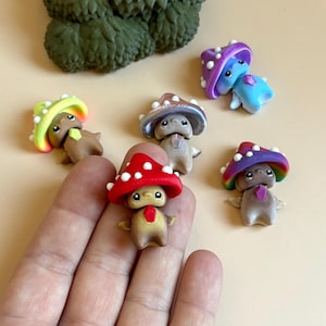 May include: A selection of charming mushroom figurines, each with a unique coloured cap and a smiling face. The mushrooms feature a variety of colours, including red, purple, blue, and green, with white polka dots. The figurines are small and detailed.