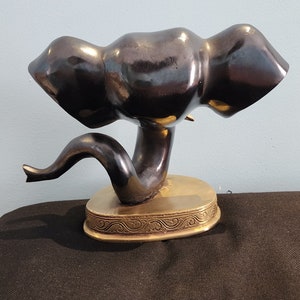 May include: A black ceramic elephant figurine with a gold base. The elephant is in a standing position with its trunk raised. The base has a decorative design.