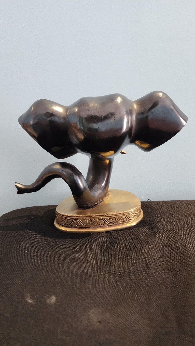 May include: A black ceramic elephant figurine with a gold base. The elephant is in a standing position with its trunk raised. The base has a decorative design.