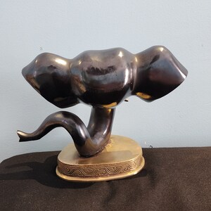 May include: A black ceramic elephant figurine with a gold base. The elephant is in a curled position with its trunk raised.