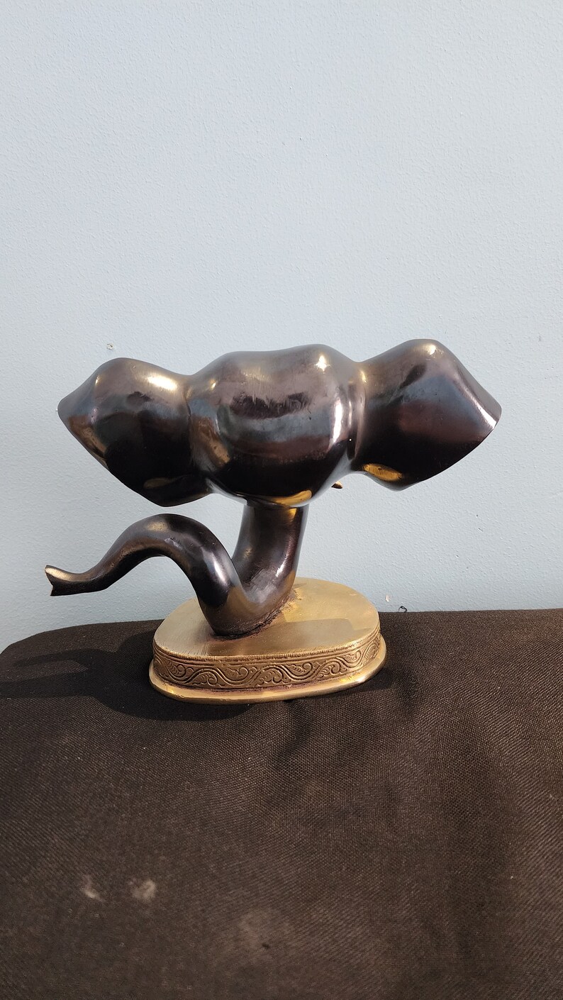 May include: A black ceramic elephant figurine with a gold base. The elephant is in a curled position with its trunk raised.